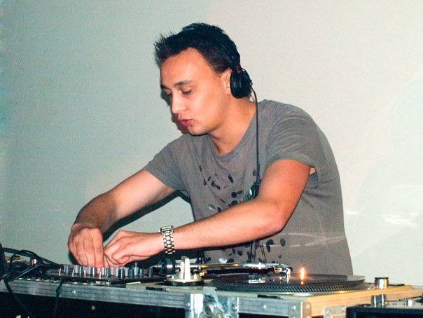 Michael Darius Eastwood mixing drum and bass on turntables, headphones on, hands on the mixer