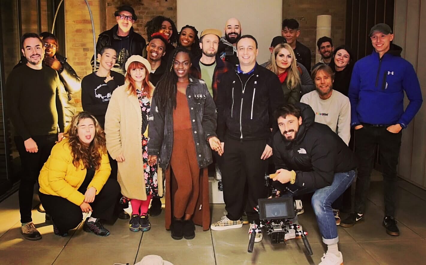 A production crew of about twenty-two people gathered around a cinema camera rig