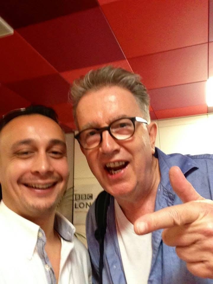 Michael Darius Eastwood with the broadcaster and musician Tom Robinson inside BBC London, the station sign visible behind them